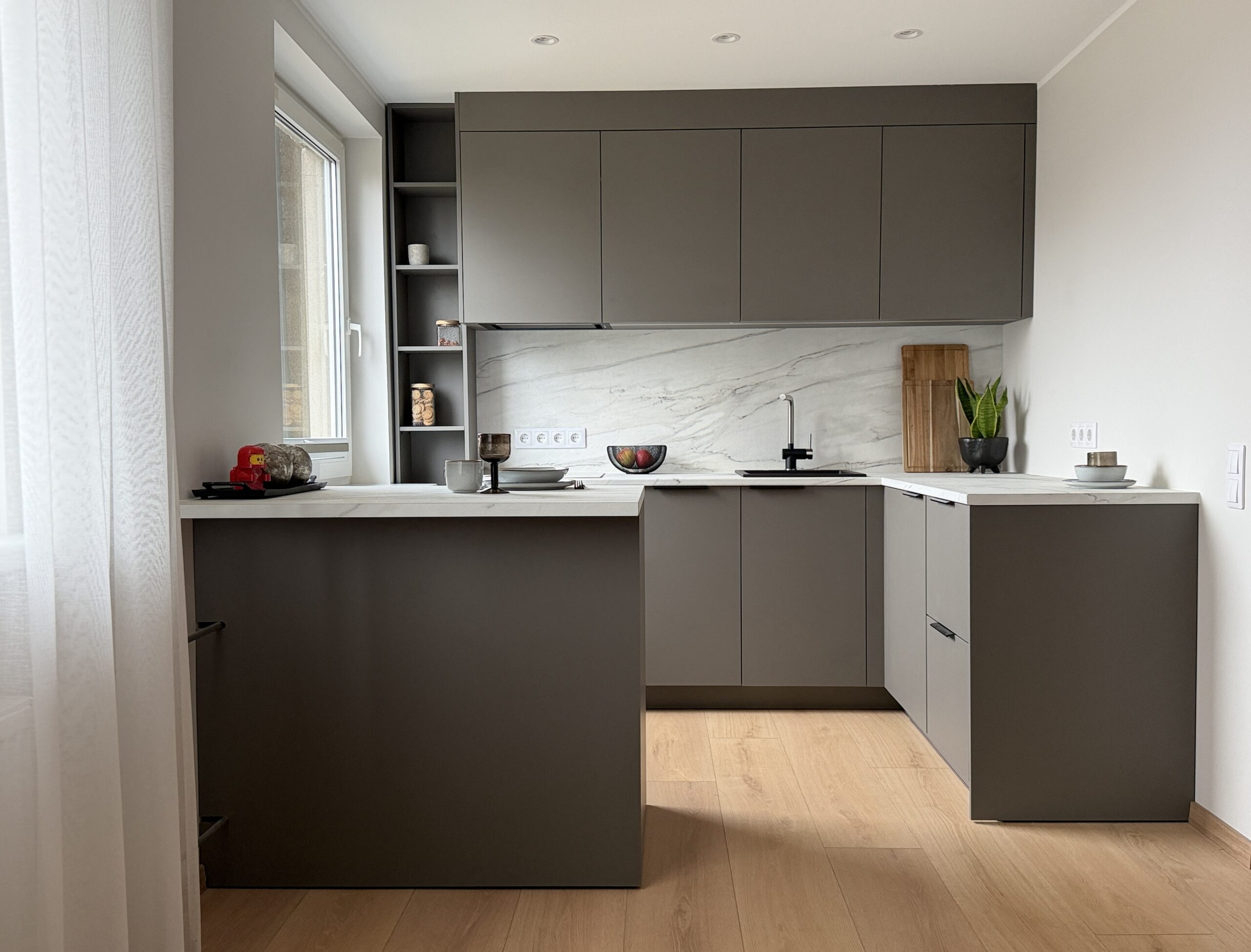 Kaasaegne hall köök Raplamaal mustade käepidemete, marmoriimitatsiooniga ja praktilise voldikkardinaga